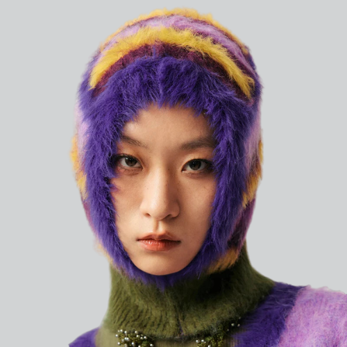 Person modeling a vibrant purple and yellow knitted balaclava design from Cambridge