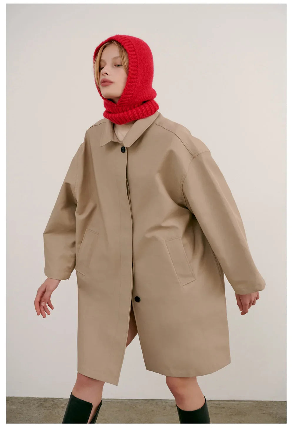 Oversized beige coat styled with a bright red knitted hood balaclava for warmth and fashion