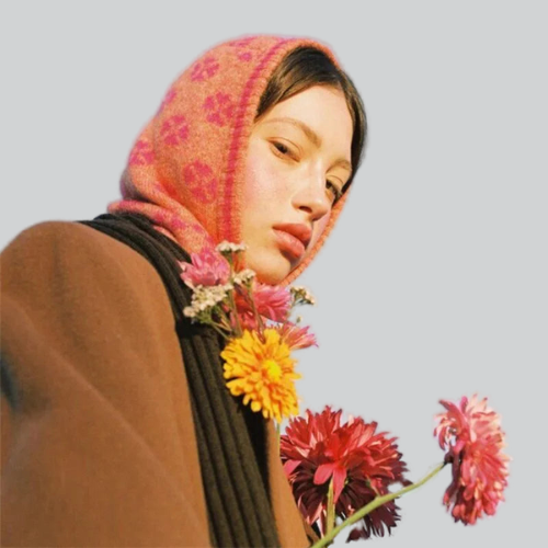 Young woman in a pink floral headscarf with flowers, showcasing a pink knitted balaclava