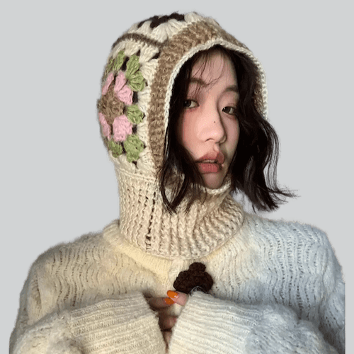 Person wearing a white knit balaclava with floral pattern over a white sweater